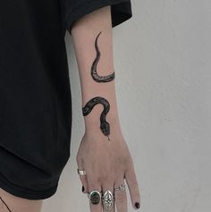 a woman's arm with a snake tattoo on it and two rings around her wrist