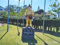 a life - sized statue of a fireman stands in front of flags and poles