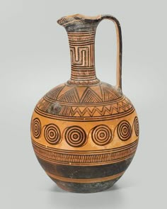 an old brown and black vase with designs on it