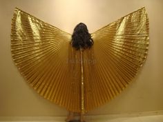 a woman standing in front of a wall with a gold fan on it's back