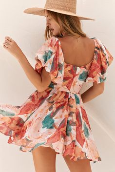 a woman in a floral print dress posing for the camera with her hand on her hip