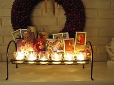 candles are lit in front of a wreath with pictures on it