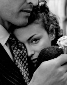 black and white photograph of a man holding a woman in his arms while she holds an apple