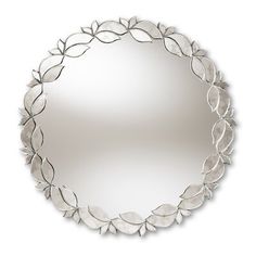 a round mirror with leaves on the bottom and an oval frame in the middle, hanging on a wall