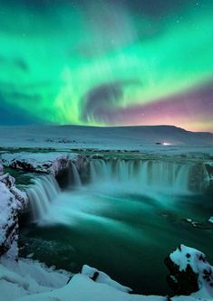 the aurora bore is seen over a frozen waterfall