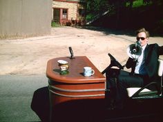 a man sitting on top of a chair holding a megaphone next to a desk