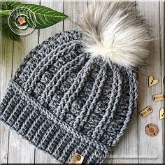 a gray knitted hat with white fur pom - pom sitting on top of it