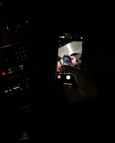 someone is holding up their cell phone to take a photo in the car at night