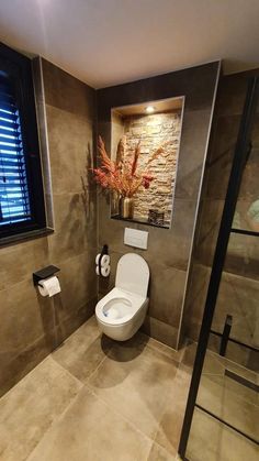 a bathroom with a toilet, window and towel rack in the corner on the wall