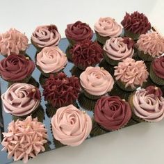 cupcakes decorated with pink and red frosting on a blue tray in front of a white wall