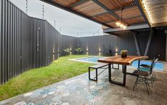 an outdoor dining area next to a swimming pool with a wooden table surrounded by chairs