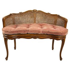 an old wooden bench with pink cushions on it's seat cushion and back rest