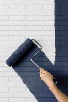 a person is painting a brick wall with a paint roller and a blue towel on it