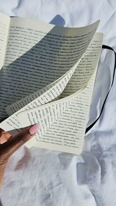 a person is holding an open book in their left hand and pointing it at the page