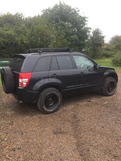 a black suv parked on top of a gravel road