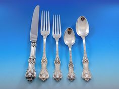 an assortment of silverware including forks, knives and spoons on a blue background