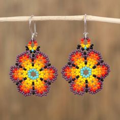 a pair of beaded earrings hanging from a wooden stick