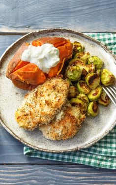 a white plate topped with fried chicken, brussel sprouts and potatoes