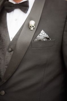 a man in a tuxedo with a skull pin on his lapel