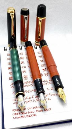 five fountain pens lined up on top of a notepad with writing in chinese and english