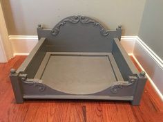 a gray bed frame sitting on top of a hard wood floor next to a wall