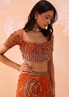 A blouse with intricate floral embroidered work and cutwork neckline paired with flora motifs sequin and zari work on skirt and dupatta. Orange Blouse Designs, Burnt Orange Lehenga, Fashion Course, Outfit Poses, Sari Traditional, Orange Lehenga, Fashionable Saree, Pre Bridal, Blouses Designs