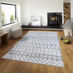 a living room with wood flooring and white rugs in front of a fire place