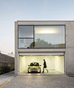 a car is parked in the garage with its door open and a person walking by