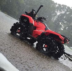 a red four - wheeler is parked on the side of a road in the rain