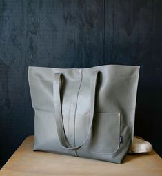 "Large gray handmade leather market tote purse is ready to ship. Large simple modern tote purse with exterior pocket and contrasting pink stitching. Leather tote is perfect for a market, library, portfolio or travel bag. -Dimensions: 19.5\" wide x 14\" high x 4.5\" deep -Strap length: 13\" - Pocket size: 5\" wide x 6\" high -GREEN DESIGN- This Tote is made from \"up-cycled\" leather, not recycled. We sought out upholstery, interior design & fabric shops' leftovers to construct this bag. This is newly treated & constructed leather, not used, that potentially otherwise would end up in a land fill. So when you purchase one, wear it proudly!" Gray Leather Shopping Bag, Gray Bags With Leather Handles, Leather Bag With Silt Pocket For Everyday Use, Gray Leather Shoulder Bag With Large Capacity, Gray Leather Bag For Everyday Use, Gray Leather Shoulder Bag For Daily Use, Gray Leather Rectangular Shoulder Bag, Soft Leather Gray Bag, Everyday Gray Soft Leather Bag