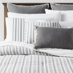 a bed with grey and white striped pillows