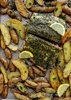 grilled salmon and potatoes on a baking sheet with lemon wedges, parsley