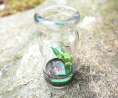 a glass jar with a plant in it sitting on a rock