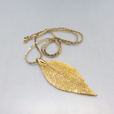 This pretty gold dipped leaf  pendant was all the rage in the 1970s. It is dipped in 24KT Gold and the veining of the leaf is just gorgeous.    It measures 3 1/4 inches tall by 1 1/4 inches wide and is in MINT, never worn condition. The bale at the top is wide enough to slip thru most any chain and it is presently situated on a 24 inch goldtone chain with a spring ring clasp.  I don't see any maker's markings.  This will arrive in a lovely gift box.   If you like old buckles, bolos or vintage je Vintage Gold Leaf Jewelry, Vintage Gold Leaf-shaped Jewelry, Rose Gold Hair Clip, Gold Hair Clips, The Leaf, 24kt Gold, Gold Dipped, Flower Hair Clips, Leaf Pendant