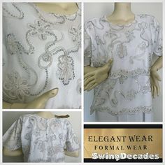 This beautiful white top with silver beading and sequins by Elegant Wear is elegant in a plus size, appropriately 2X. It has never been worn, new with tags.  It is comfortable with a zipper back and three quarter length sleeves, clean and can be hand washed, air dried.  Approximate Measurements: Bust 50" Waist 48" Hips 54" Length 25.5" Sleeve length 13" Labeled 2X, measures, like between current 2X and 3X. Please measure carefully for a perfect fit.  This has never been worn and still has the or White Short Sleeve Tops For Evening, White Embellished Tops For Festive Occasions, Elegant Beaded Short Sleeve Tops, White Embellished Tops For Formal Occasions, Elegant Short Sleeve Holiday Tops, Elegant White Festive Top, Formal Embellished White Tops, Silver Tops For Summer Wedding, Silver Embellished Tops For Wedding