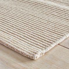 a close up view of a beige rug on a wooden floor with white lines in the middle