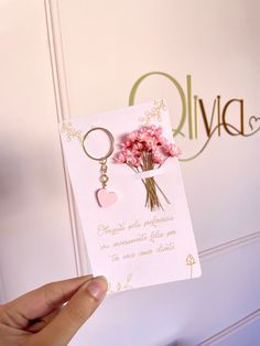 a person holding a card with flowers in it and a keychain attached to it