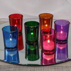 several different colored glass candles on a tray