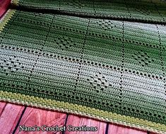 a green crocheted blanket sitting on top of a wooden floor