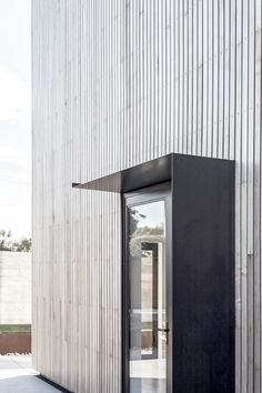 an open door on the side of a building with wood slats covering it's walls