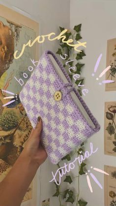 a hand holding up a crocheted purple and white purse with buttons on it