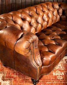 a brown leather couch sitting on top of a rug