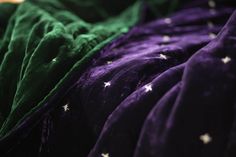 green and purple sheets with white stars on them are folded up in a row to be used as bedspreads