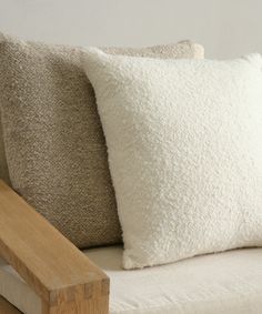 two white pillows sitting on top of a wooden bench