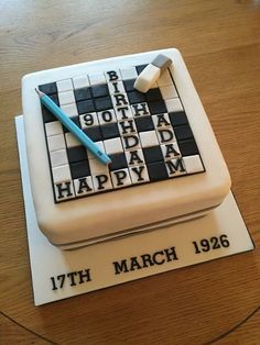 a birthday cake made to look like a crossword puzzle piece with a pen on top