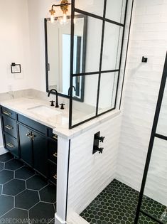 a bathroom with black and white tile flooring and a large mirror on the wall