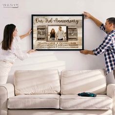 a man and woman are holding up a framed anniversary photo with the couple's names on it