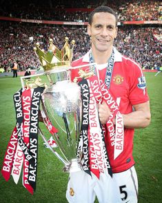 a man holding up a trophy on top of a field