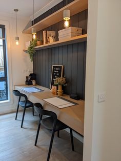 a desk with two chairs next to it and a book shelf on the other side