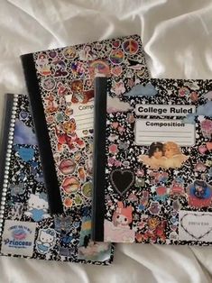 two notebooks sitting on top of a bed covered in stickers and writing paper